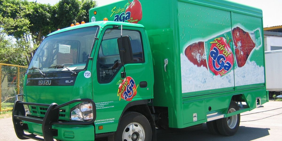 Isuzu Caja Seca verde rotulado con imagen de Sidral Aga
